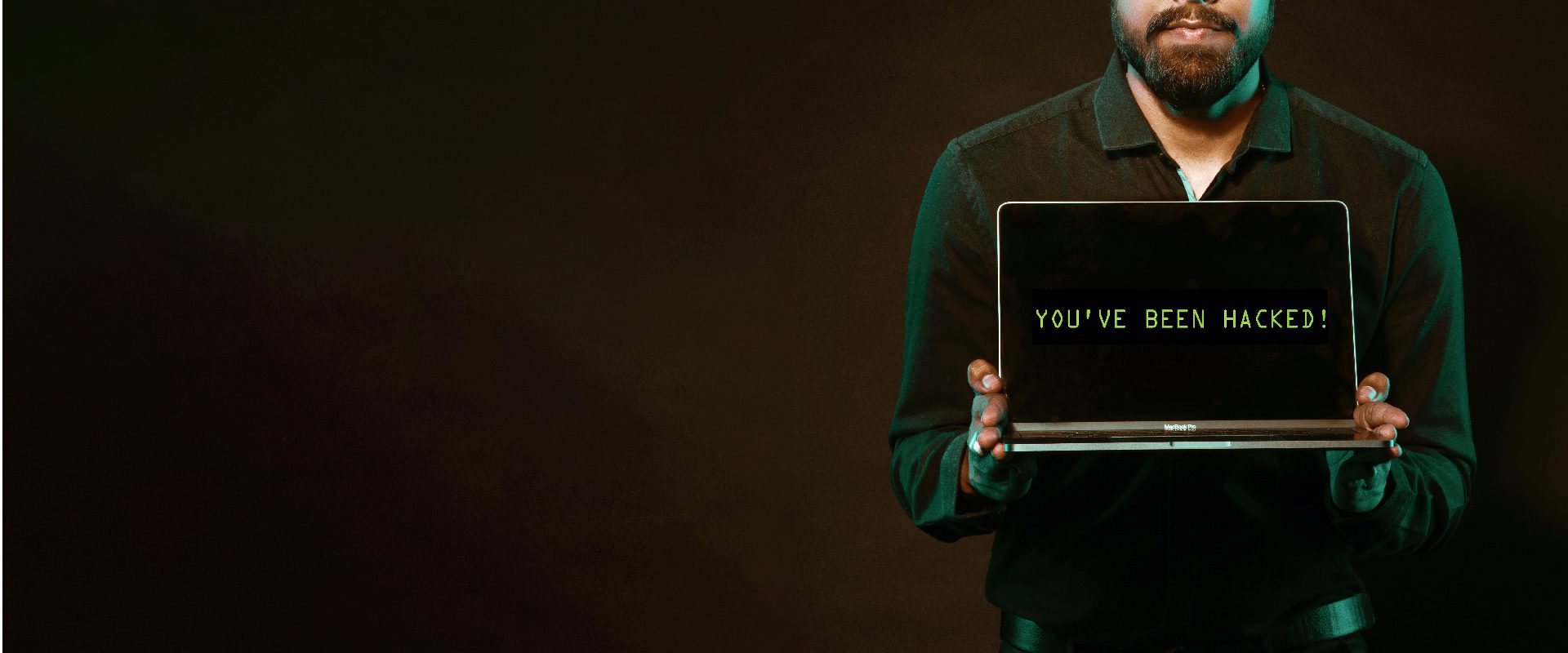 Businessman holding laptop that says 'you've been hacked'
